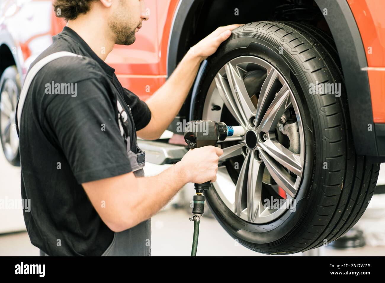Car mechanic in a workshop changing tire Stock Photo