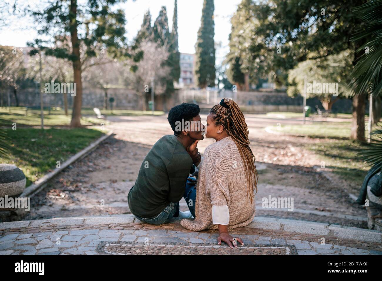 Teenage boy kissing his mother in a park Stock Photo