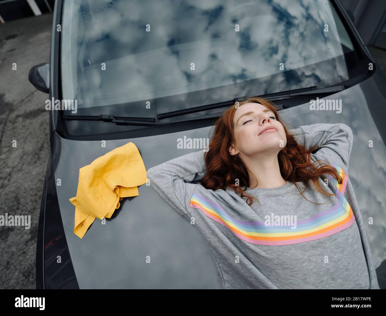 Redheaded woman lying on car Stock Photo Alamy