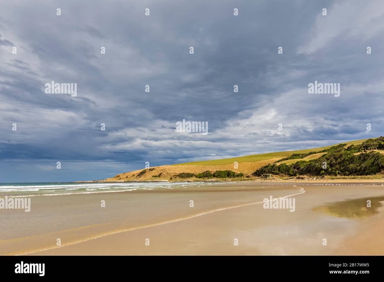 New Zealand, Cloudy sky over sandy coastal beach of Purakaunui Bay Stock Photo