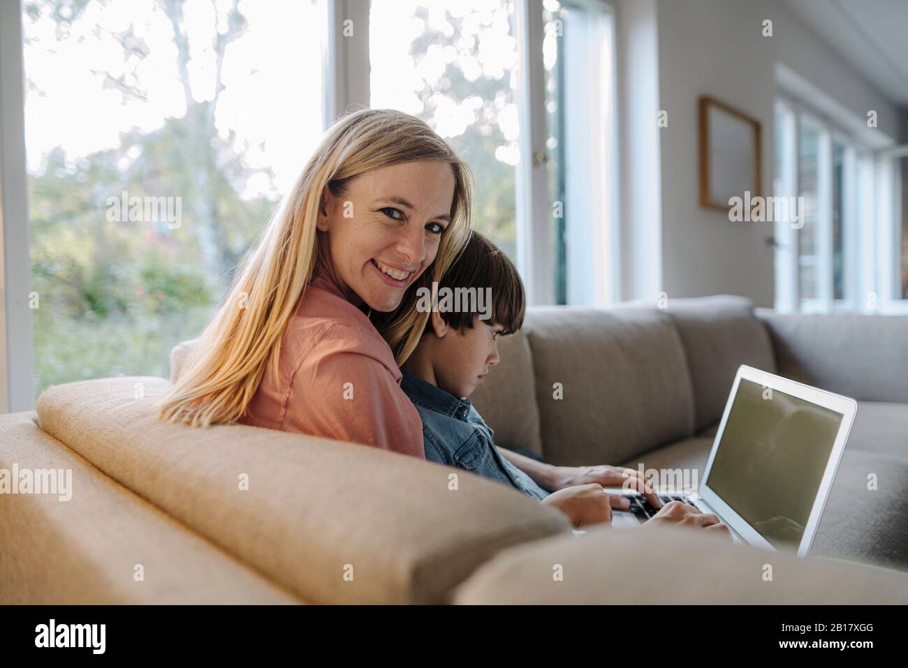 Mother and son sitting on couch, using laptop Stock Photo