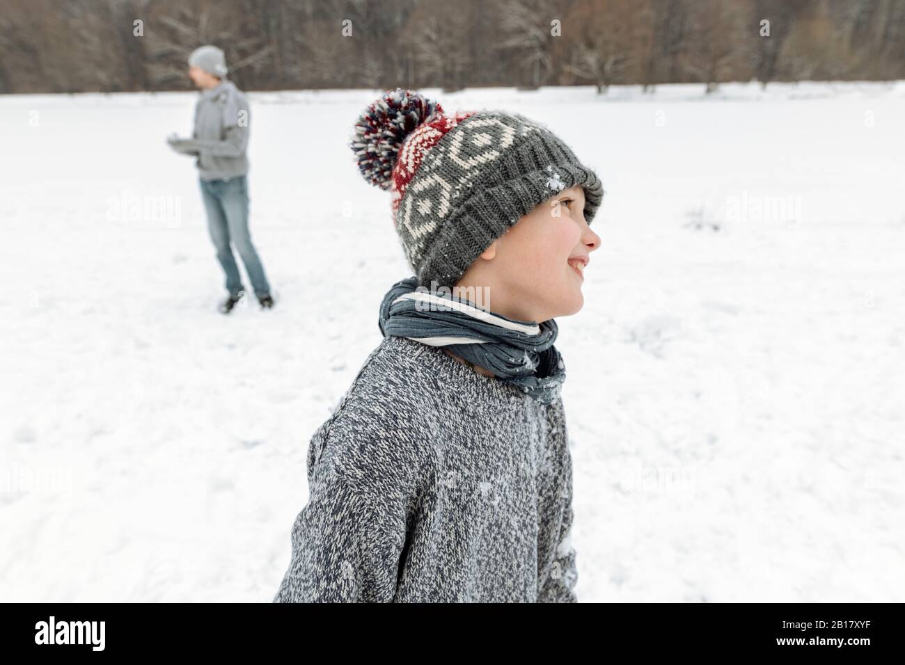 Portait of smiling boy in winter landscape with father in background Stock Photo