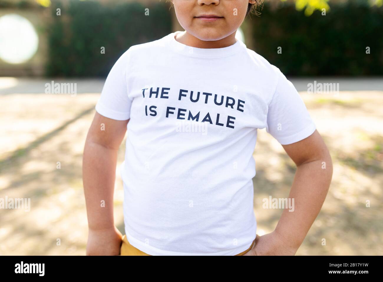 Proud little boy standing in the street with print on t-shirt, saying the future is female Stock Photo