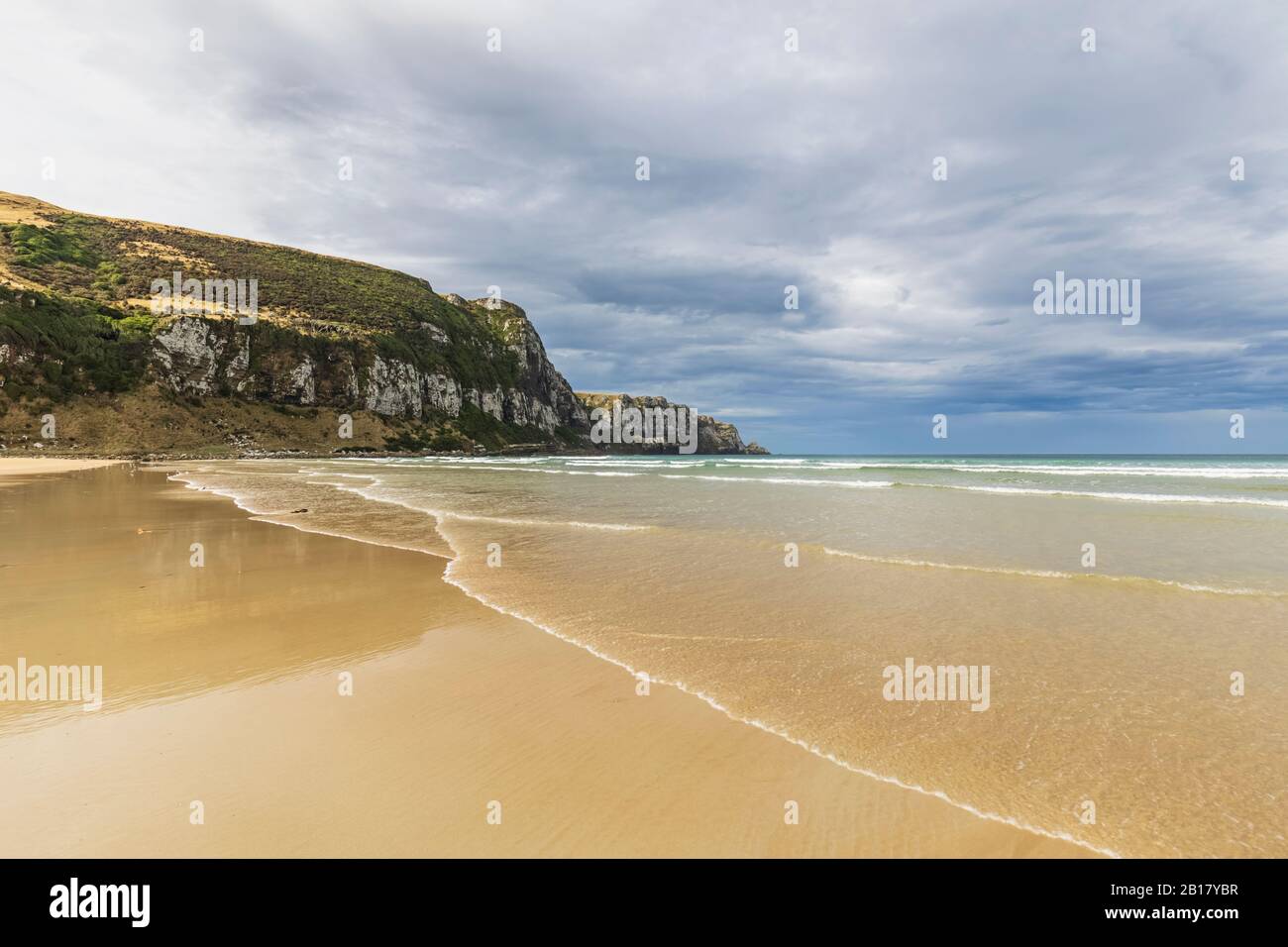 New Zealand, Cloudy sky over sandy coastal beach of Purakaunui Bay Stock Photo