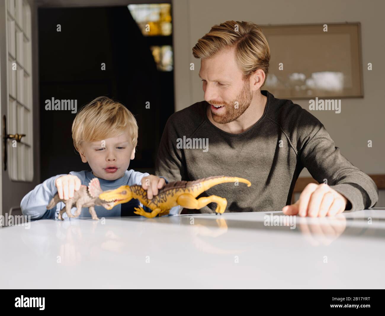 Father and son playing with dinosaur figures at home Stock Photo