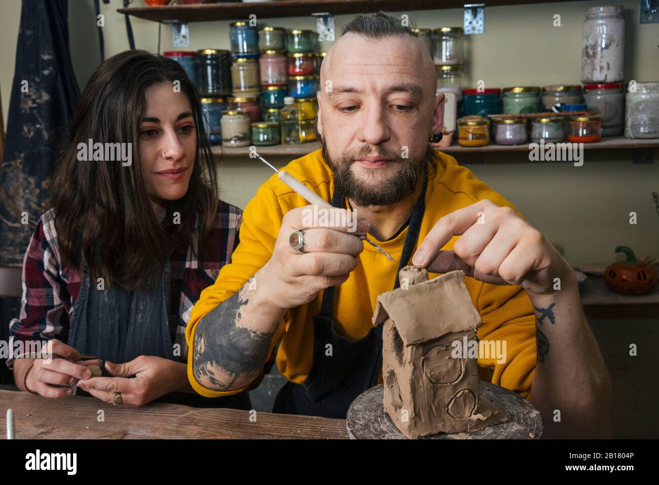 Two potters working together on a small house in workshop Stock Photo ...