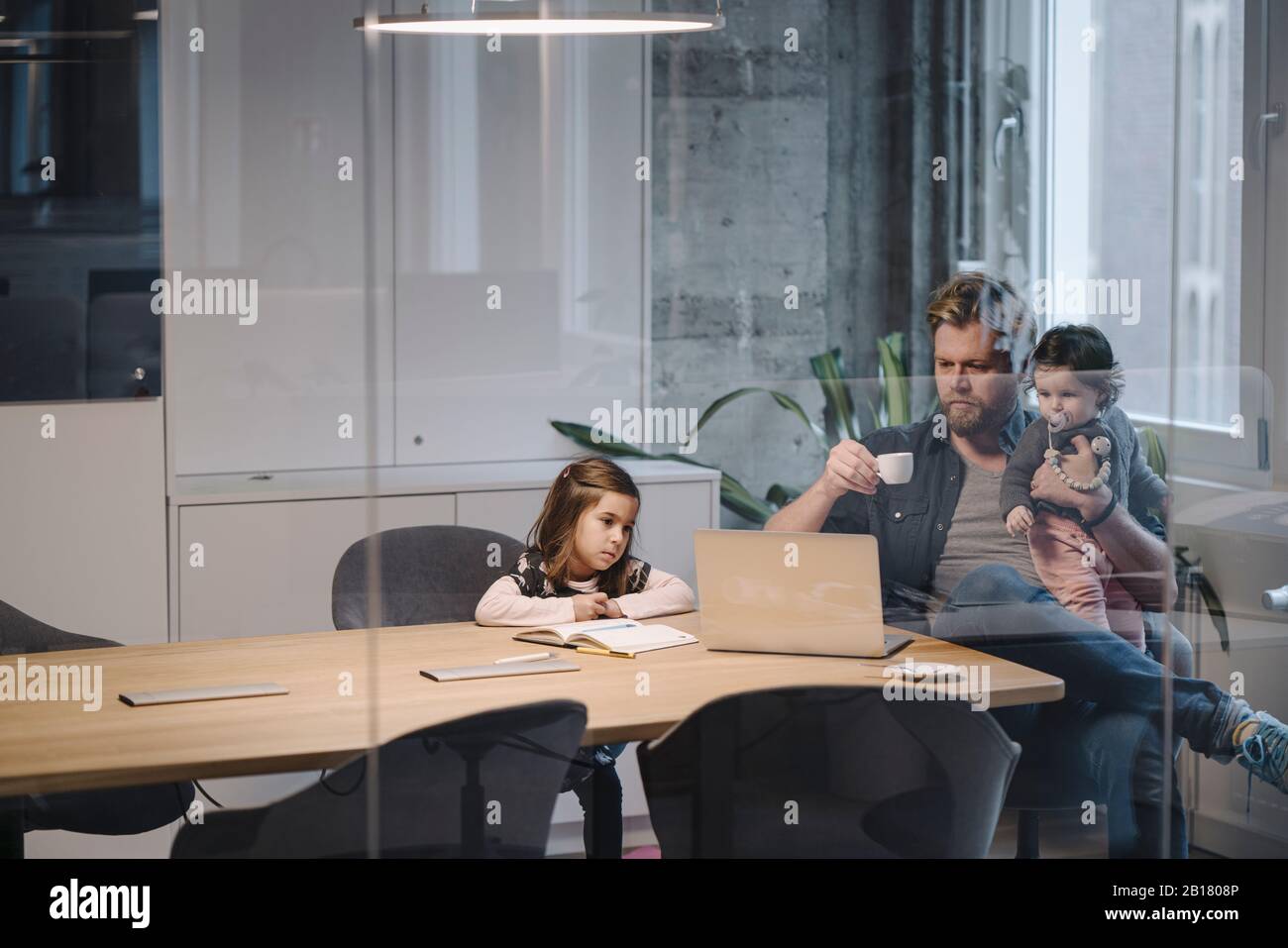 Casual businessman with two daughters working at desk in office Stock Photo