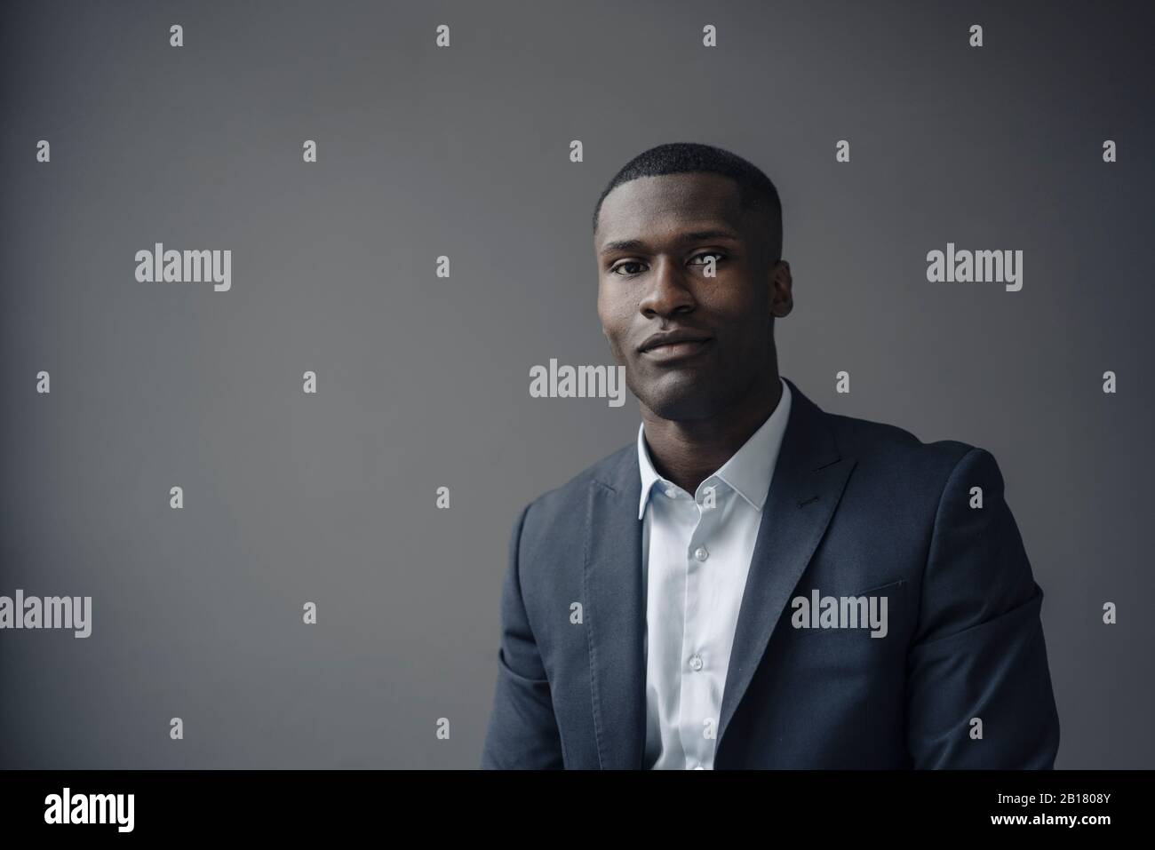 Portrait of young businessman against grey background Stock Photo - Alamy