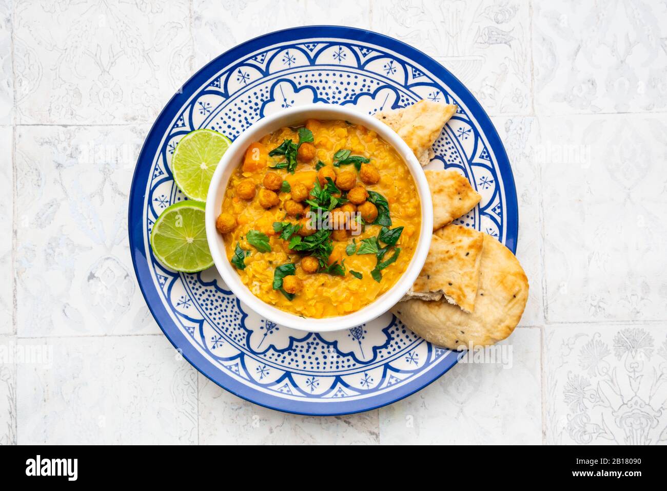 Vegan lentil curry with red lentils, sweet potatoes, spinach, roasted turmeric, chickpeas, with lime juice and coriander and naan bread Stock Photo