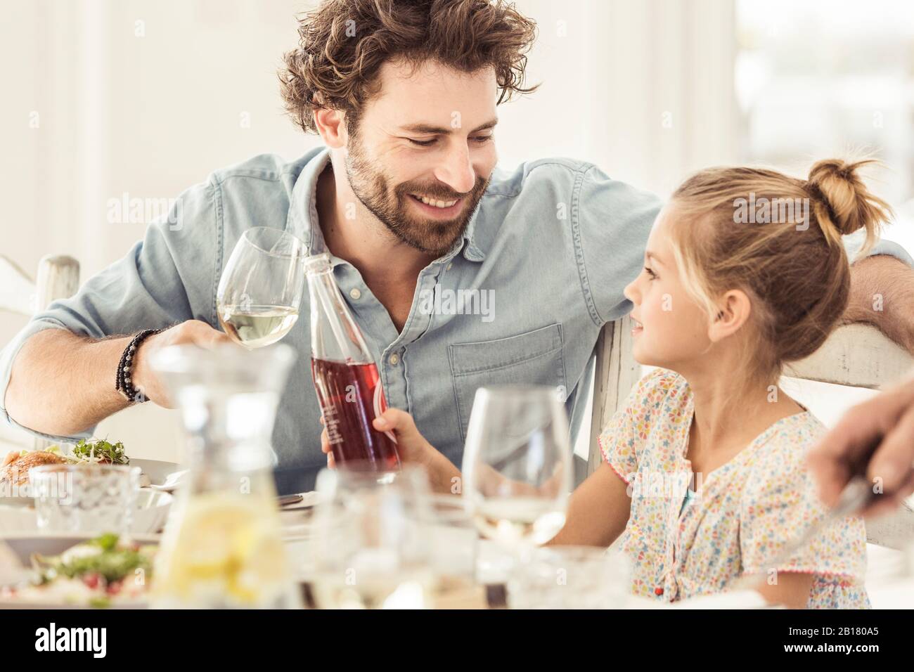 Father and daughter sitting at dining table toasting Stock Photo