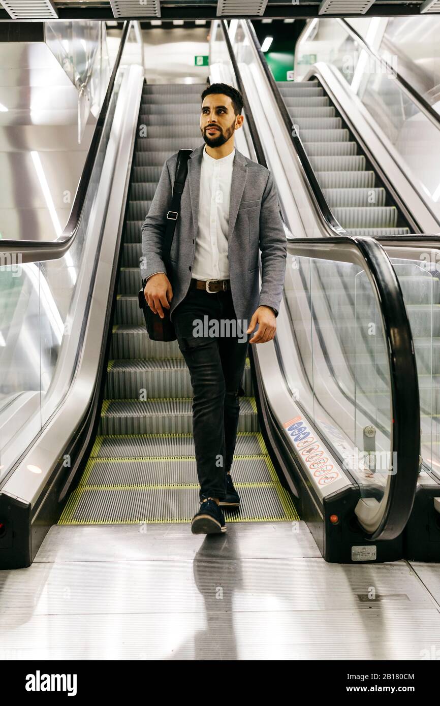 Casual young businessman on escalator Stock Photo