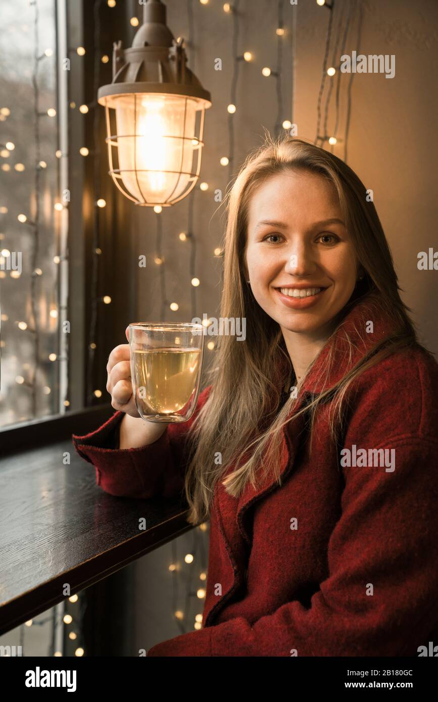 Portrait of smiling young woman with glass of tea in a coffee shop Stock Photo