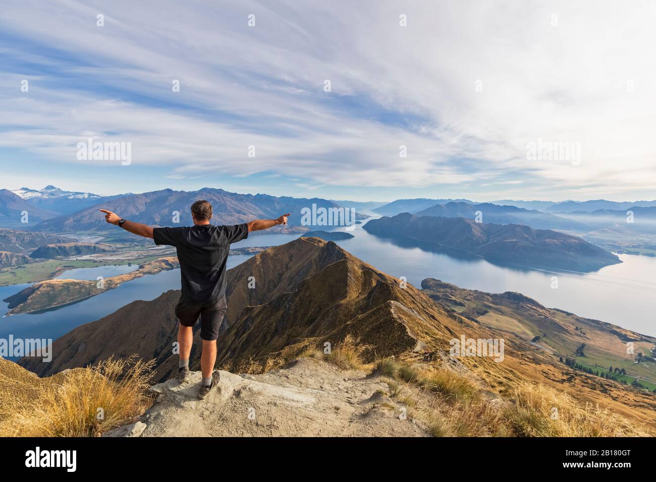 Hiker standing on viewpoint at Roys Peak, looking to Mount Aspiring, Lake Wanaka, South Island, New Zealand Stock Photo