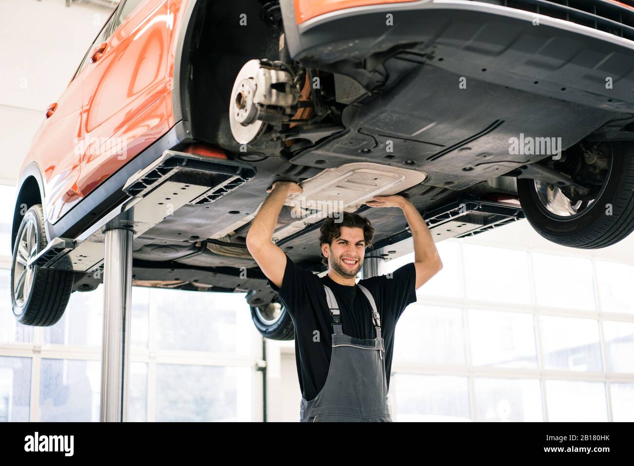 Portrait of a car mechanic in a workshop pretending to lift up a car Stock Photo