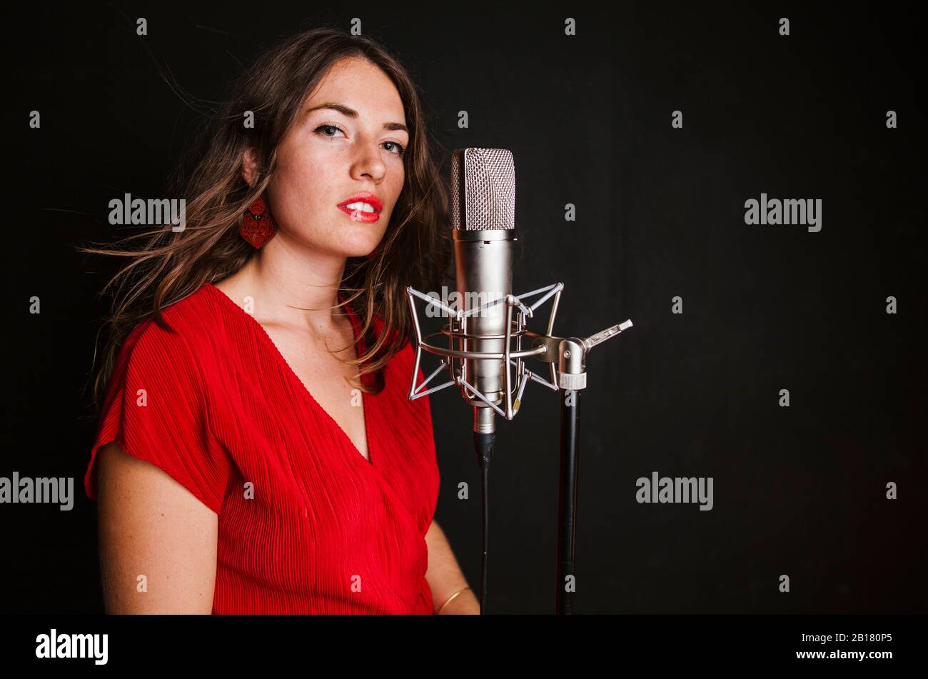 Portrait of female singer with microphone, wearing red dress Stock Photo
