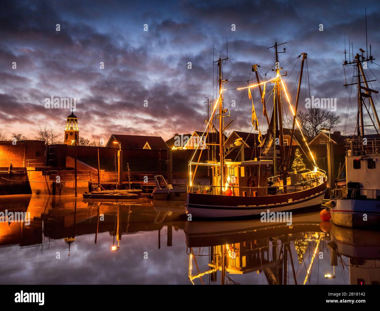 Germany, Lower Saxony, Landkreis Leer, Friesland, Ditzum, Ship illuminated for Christmas at dusk Stock Photo