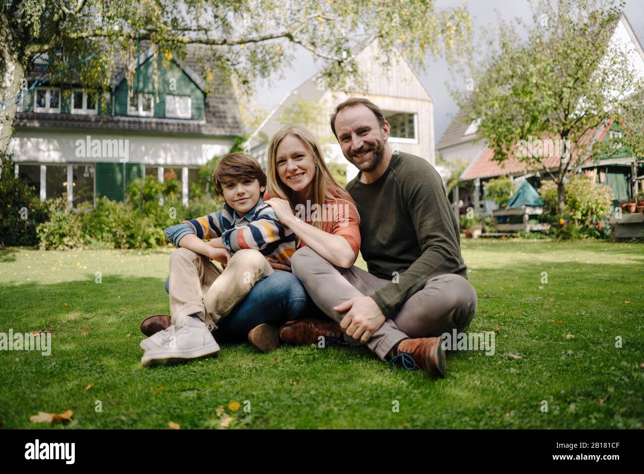 Happy family sitting on grass in their garden Stock Photo - Alamy