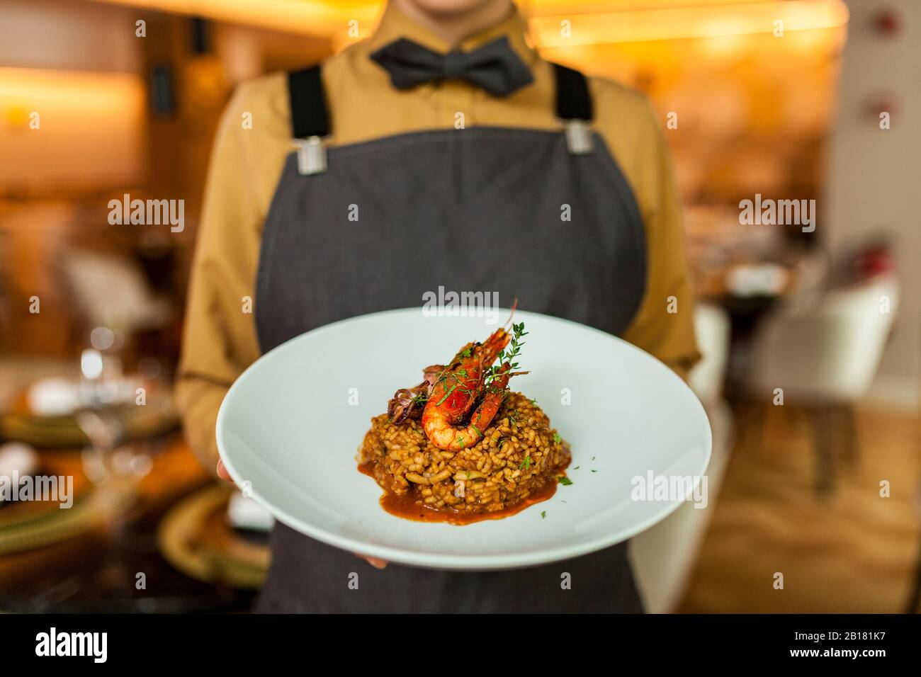 Waitress serving paella on white plate Stock Photo