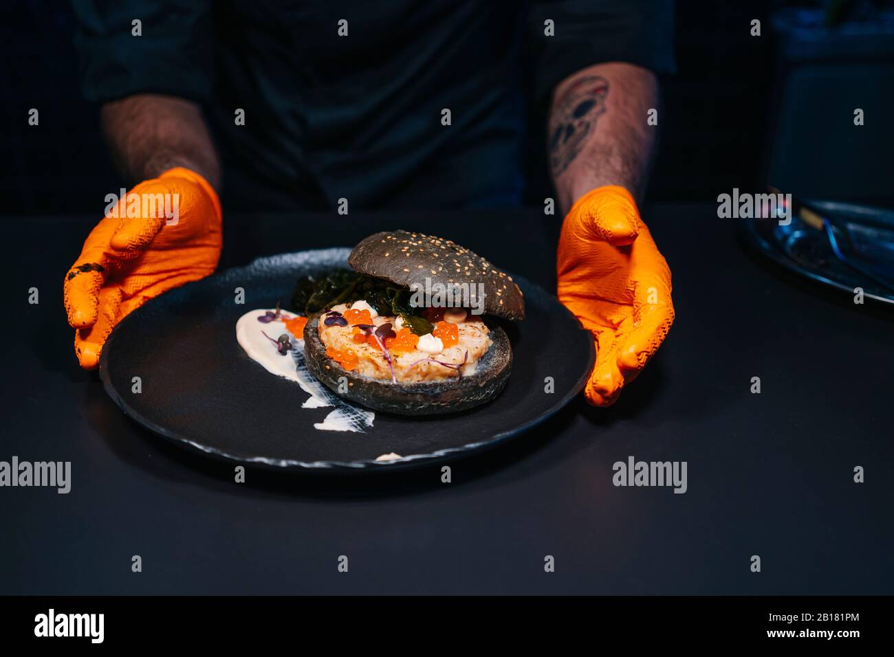 Close-up of chef presenting a burger dish in restaurant kitchen Stock Photo