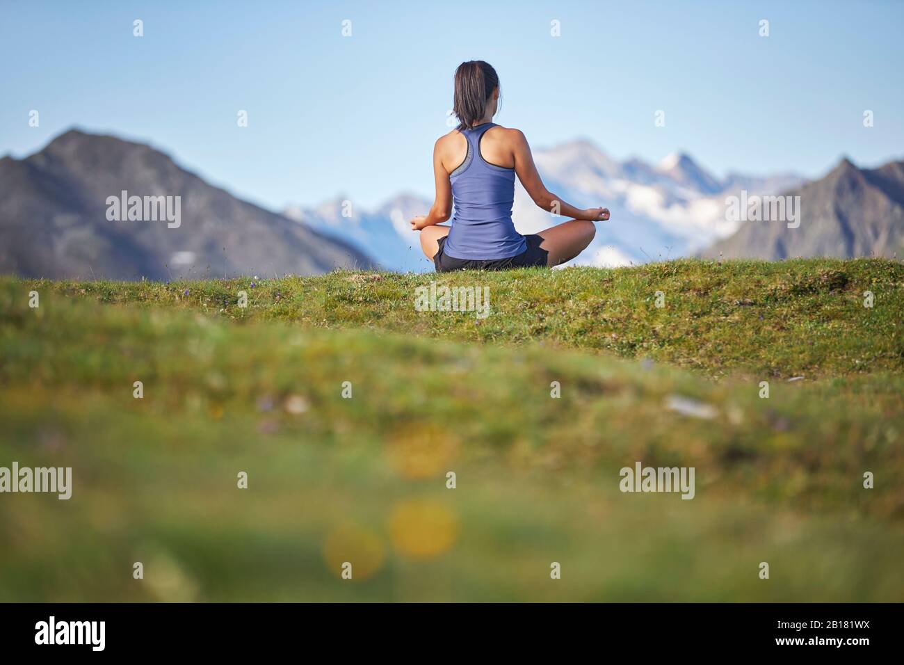 Woman meditating in the mountains, rear view Stock Photo