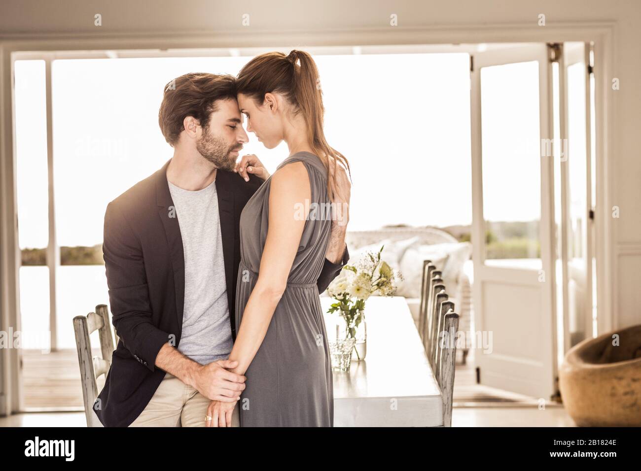 Affectionate young couple at dining table with view on terrace Stock Photo