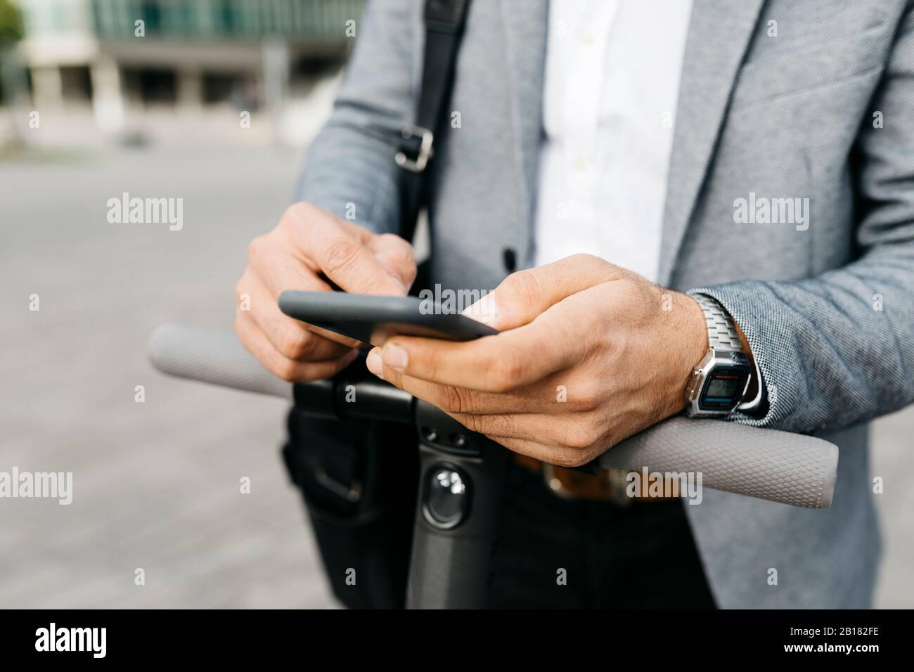 Close-up of businessman with electric scooter using cell phone Stock Photo