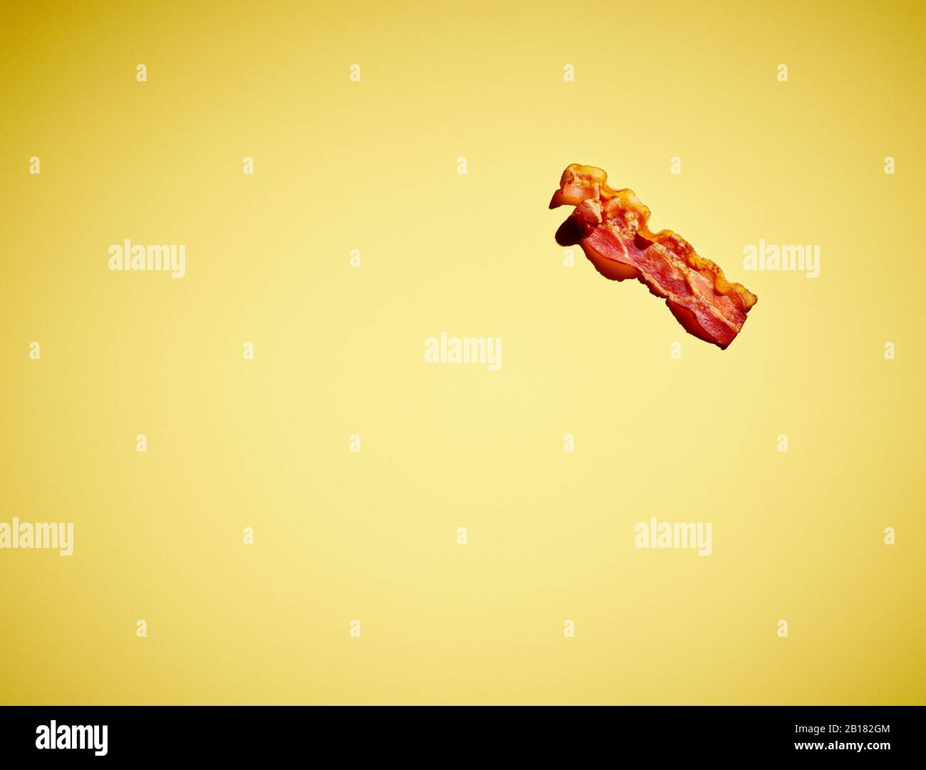 Studio shot of single bacon strip against yellow background Stock Photo