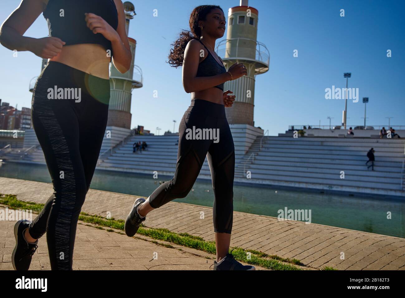 Two sportswomen jogging at a lake in the city, Barcelona, Spain Stock