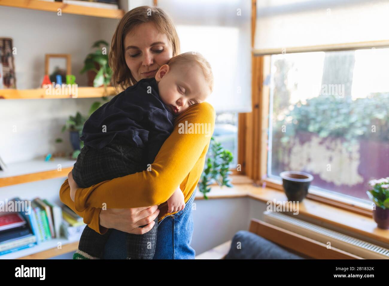 Mother holding her sleeping son on her shoulder Stock Photo