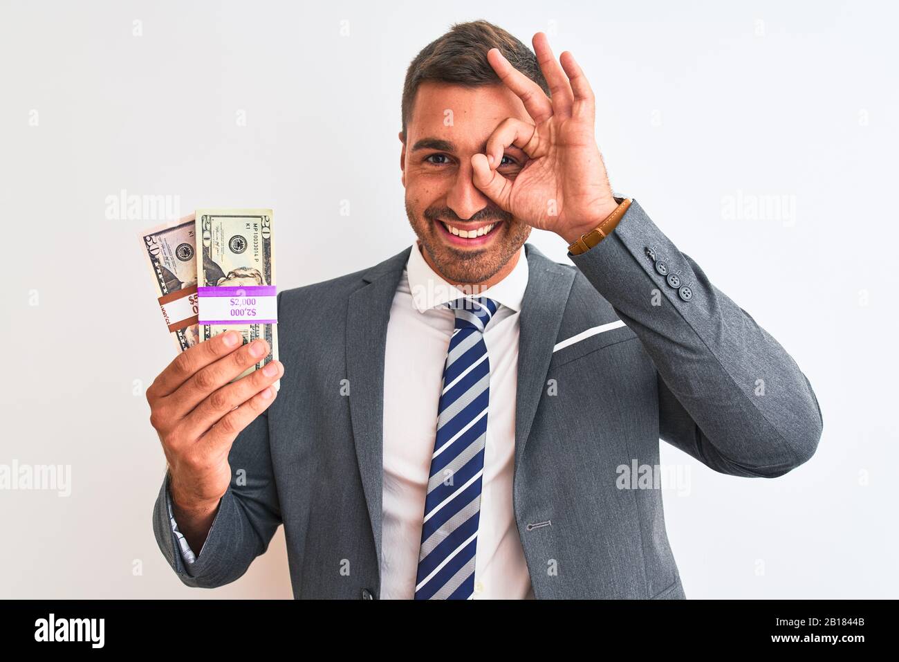 Young handsome business man holding bunch of dollars banknotes over ...