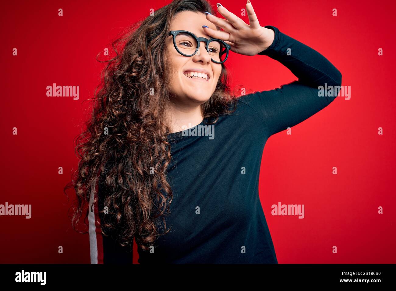 Young beautiful woman with curly hair wearing sweater and glasses over ...