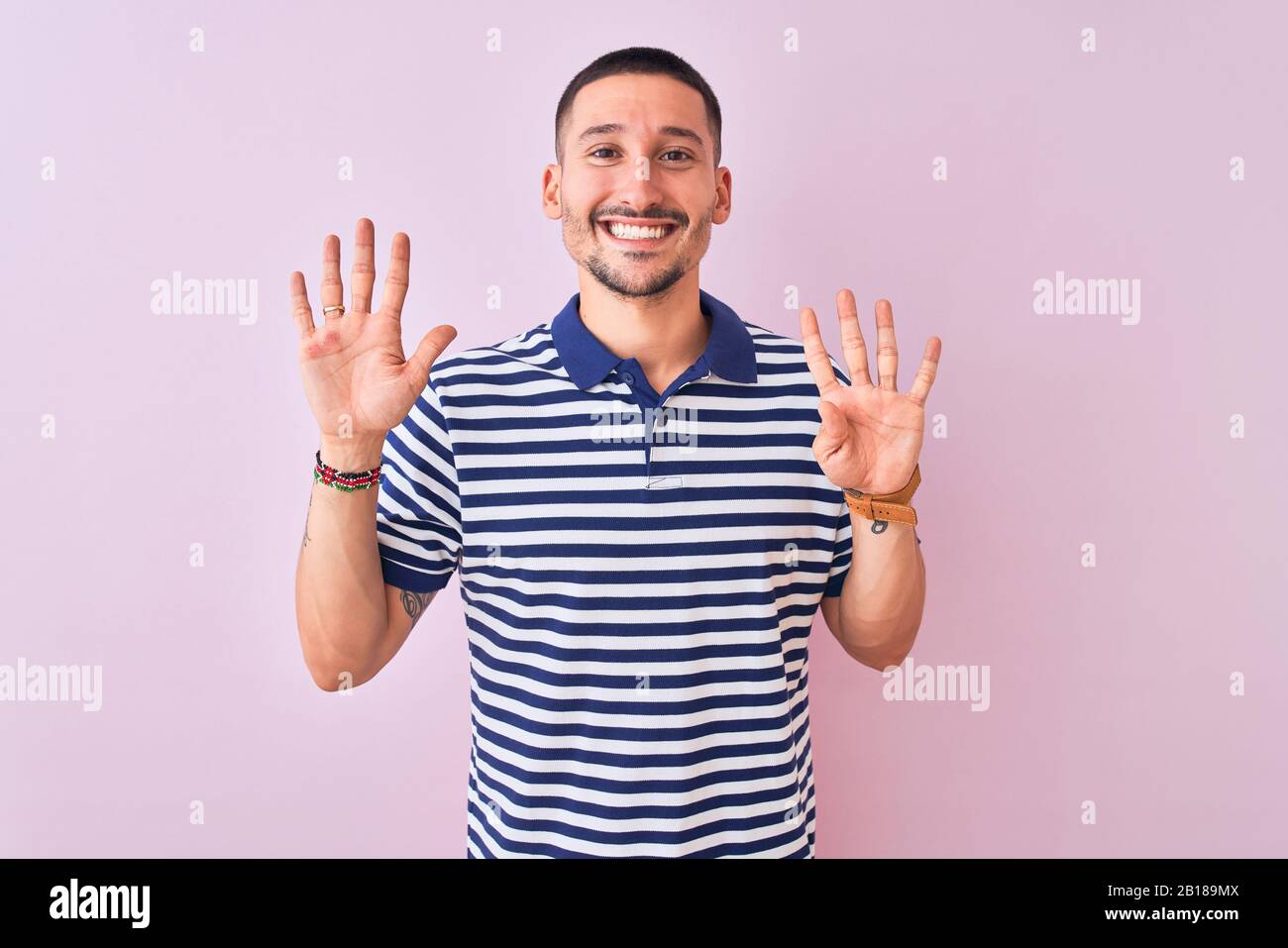 Young handsome man wearing nautical striped t-shirt over pink isolated