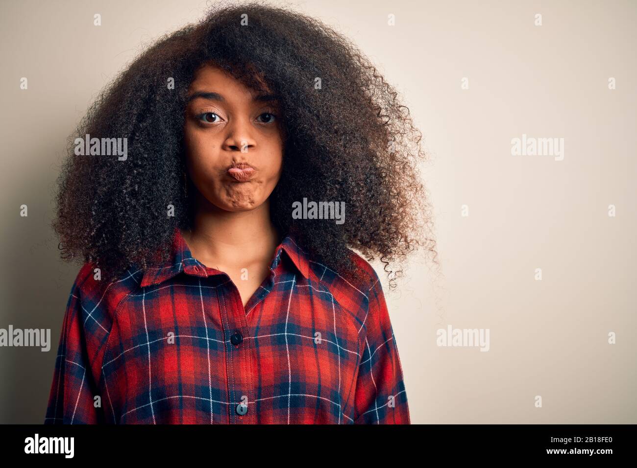 Young beautiful african american woman wearing casual shirt over isolated background puffing cheeks with funny face. Mouth inflated with air, crazy ex Stock Photo