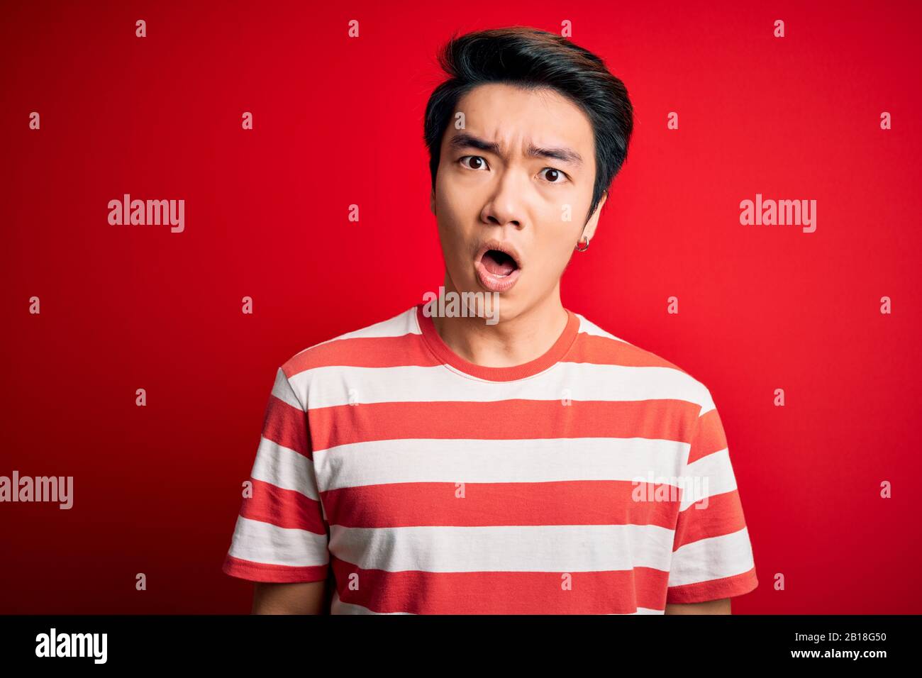 Young Handsome Chinese Man Wearing Casual Striped T Shirt Standing Over Red Background In Shock Face Looking Skeptical And Sarcastic Surprised With Stock Photo Alamy