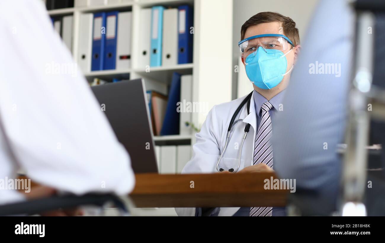 Male doctor suspiciously looks at patient suspects severe stage of virus Stock Photo