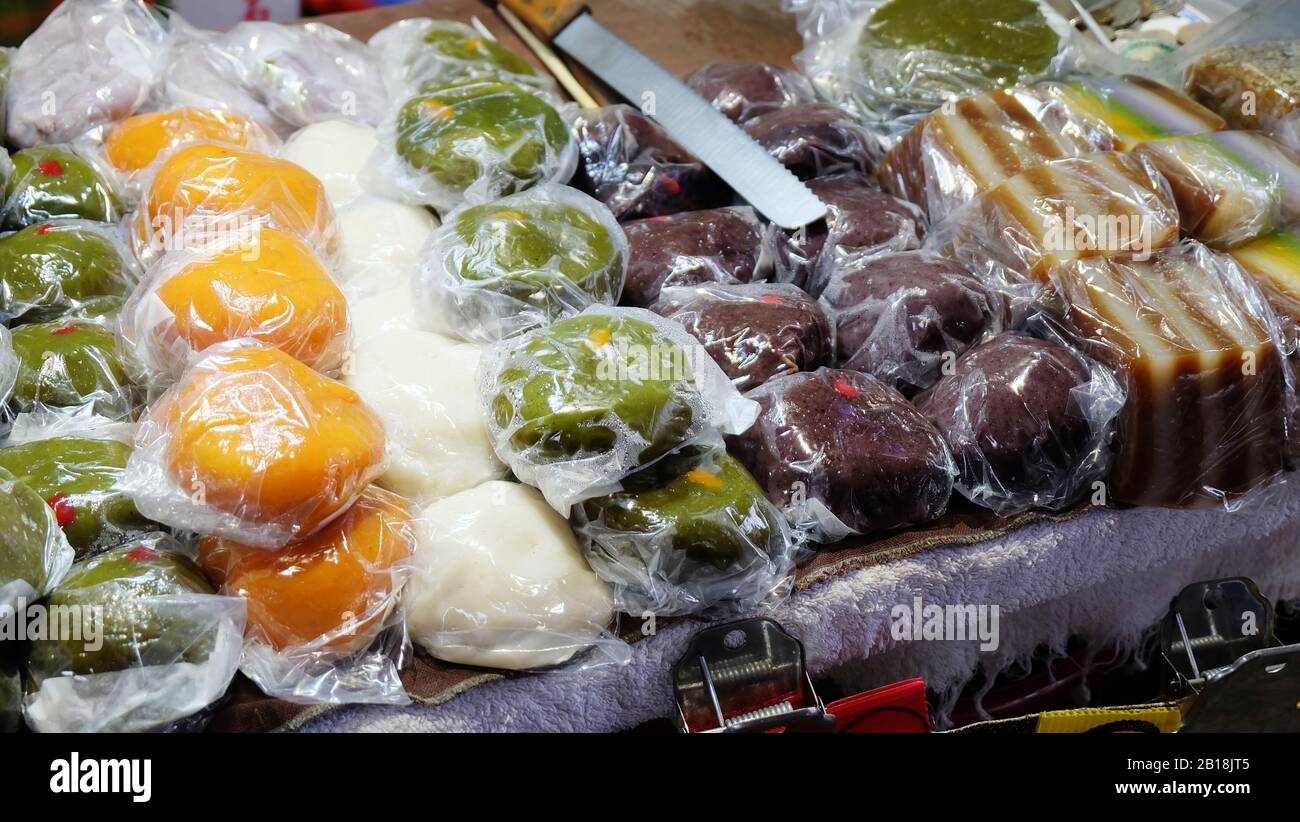 A variety of steamed rice cakes and pastries, individually wrapped in plastic wrappings, on display for sale. Stock Photo