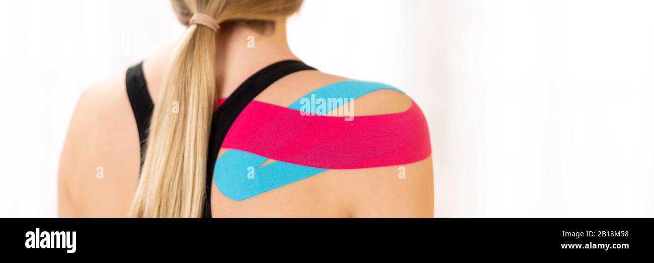 Rear view of a female patiet with kinesio tape on her shoulder. Kinesiology, physical therapy, rehabilitation banner. Stock Photo
