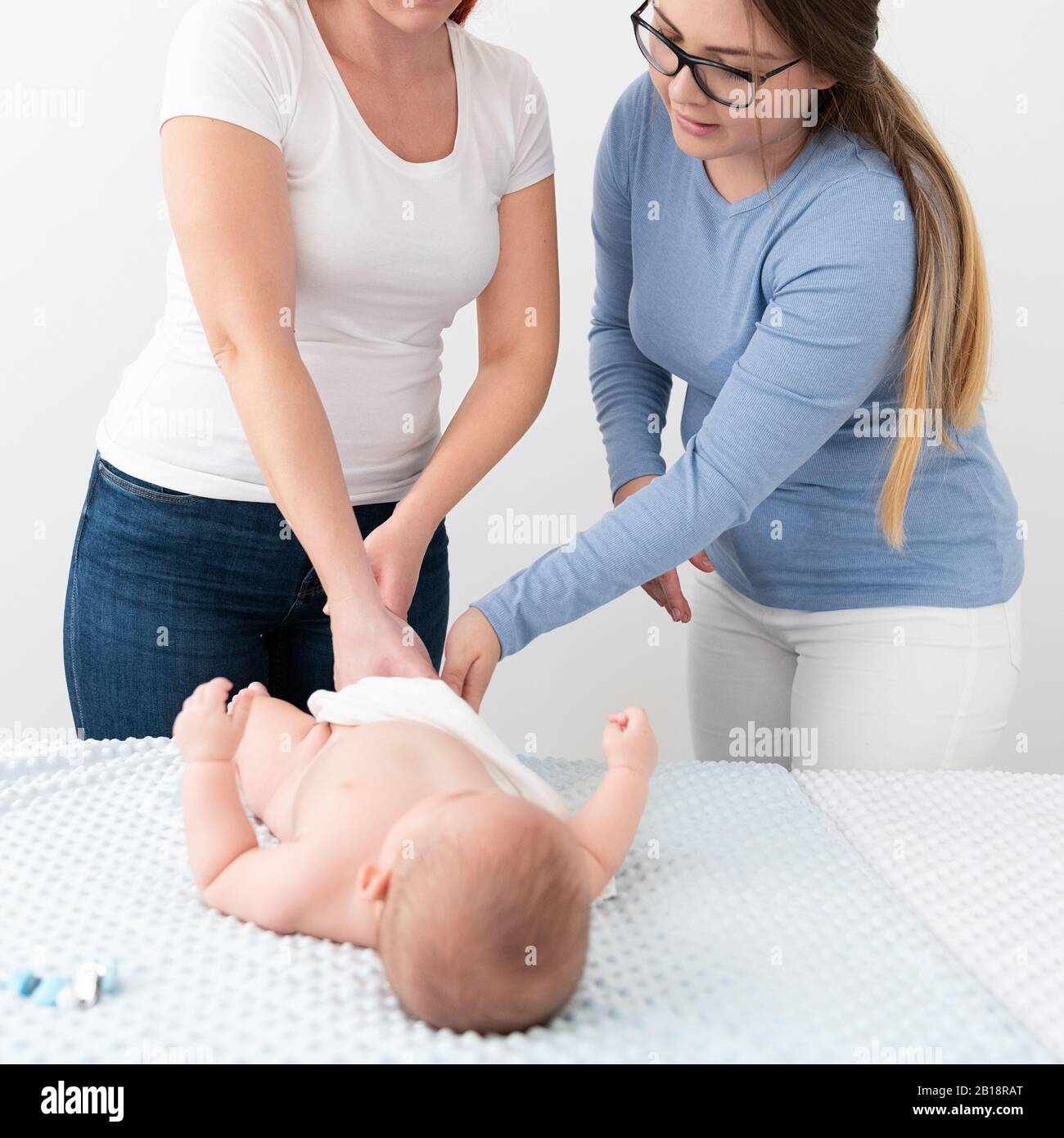 Female massage therapist teaching young mother how to massage her