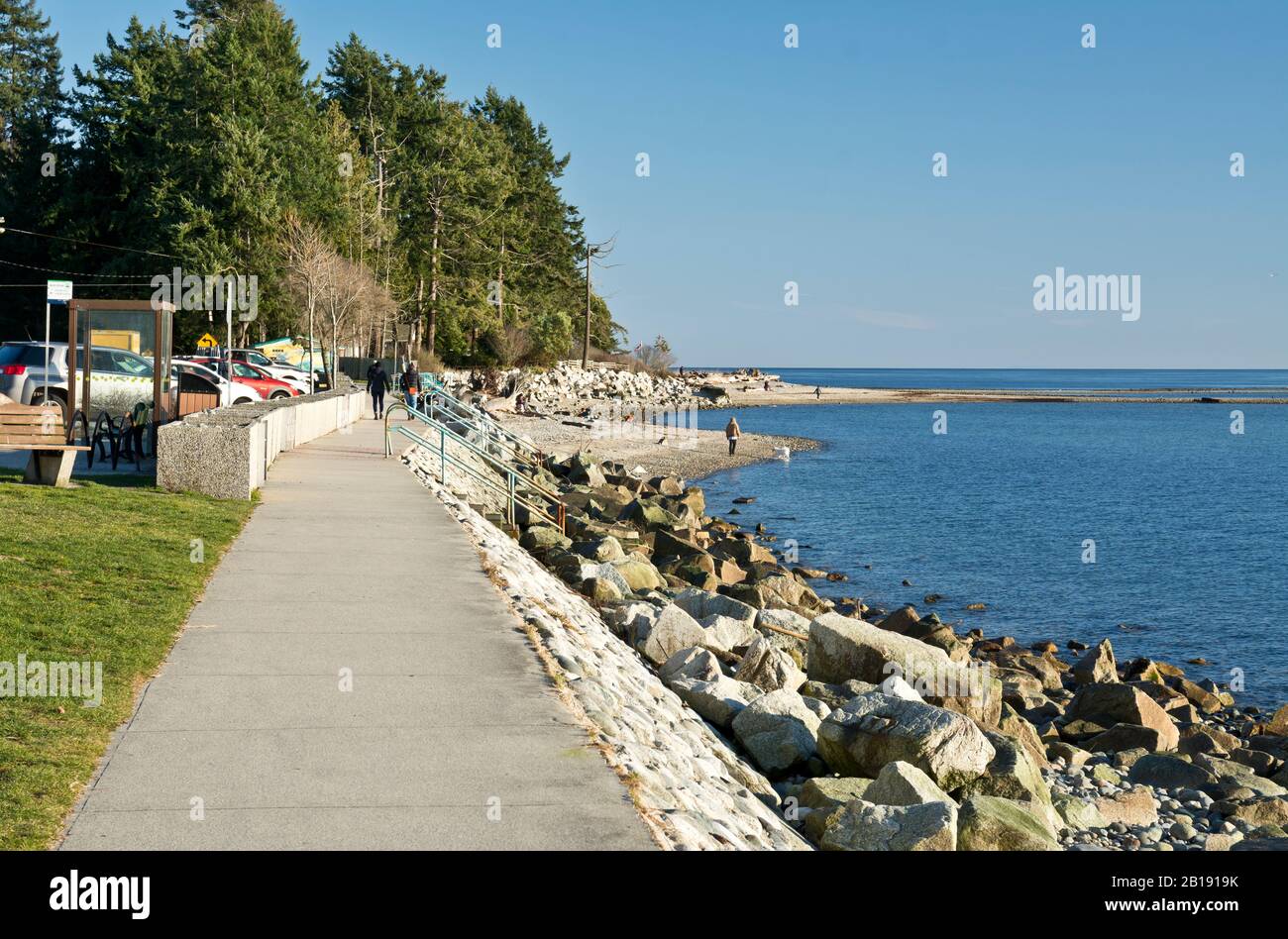 People walking along the seawall and shoreline at Davis Bay, BC, on the Sunshine Coast on a sunny Winter day. Stock Photo