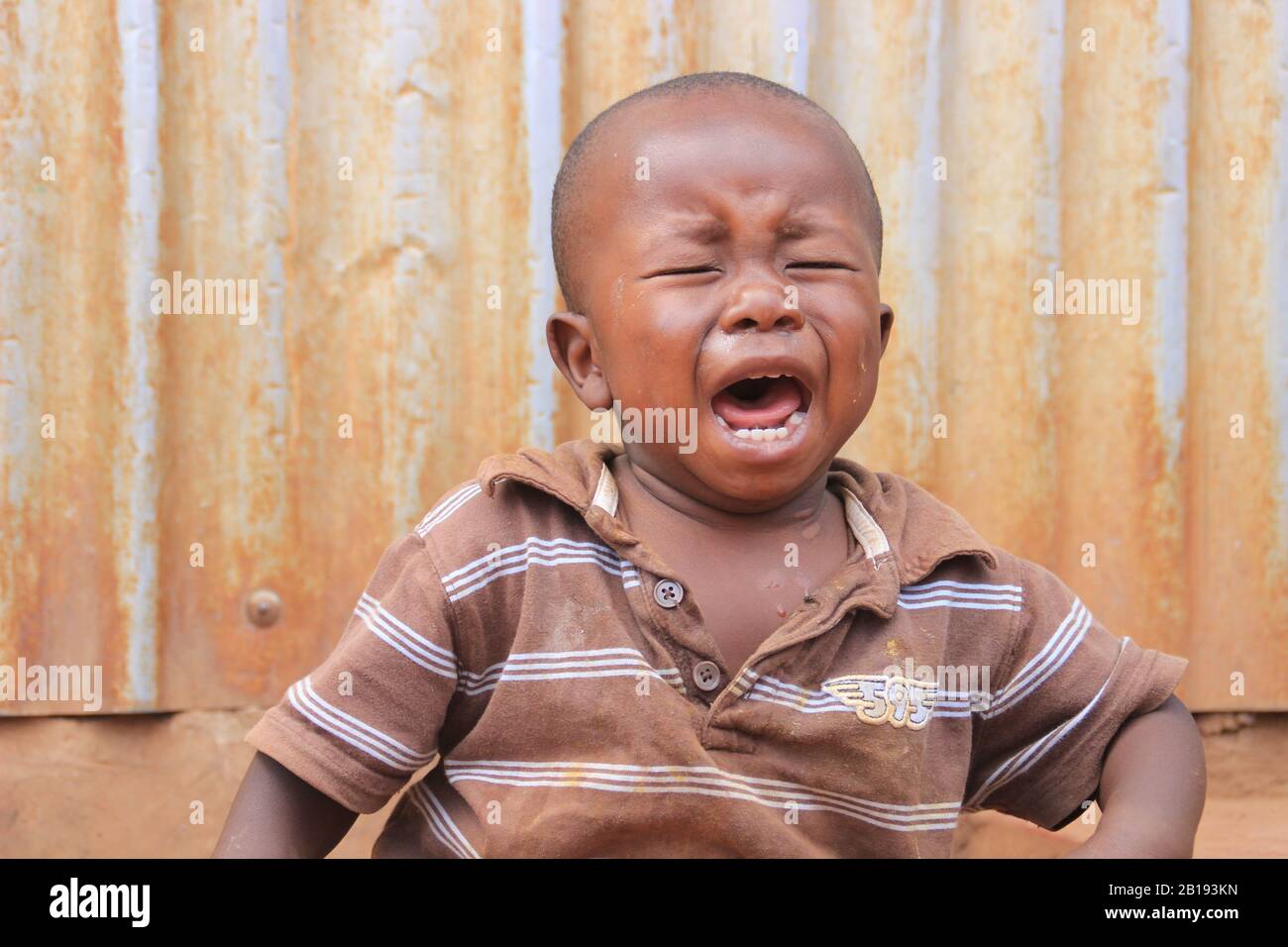 Kibera, Nairobi, Kenya - February 13, 2015: A little dirty poor African child crying out loud Stock Photo