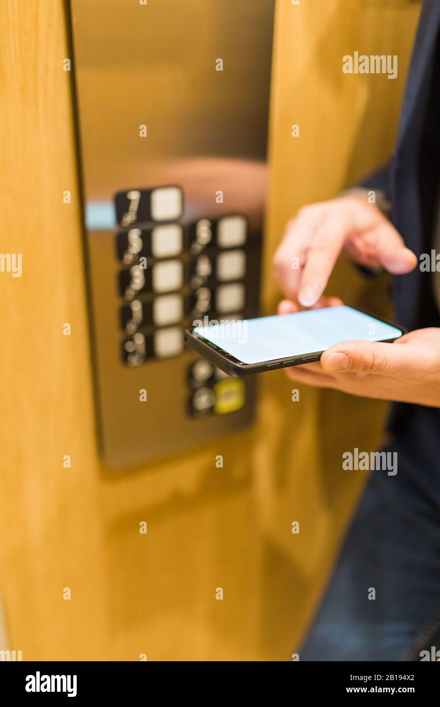 Man hands holding blank screen mobile phone in elevator Stock Photo