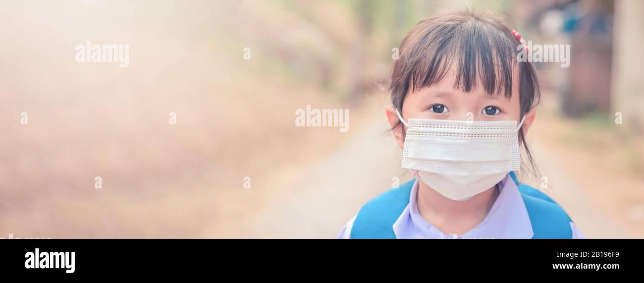 Little school girl has mask protect herself from Corona virus COVID-19 when child go to school,Student with a mask on her nose for safety from illness Stock Photo
