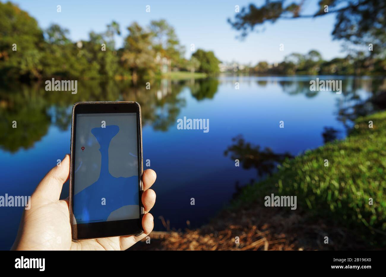 Man using mobile map app next to the lake Stock Photo