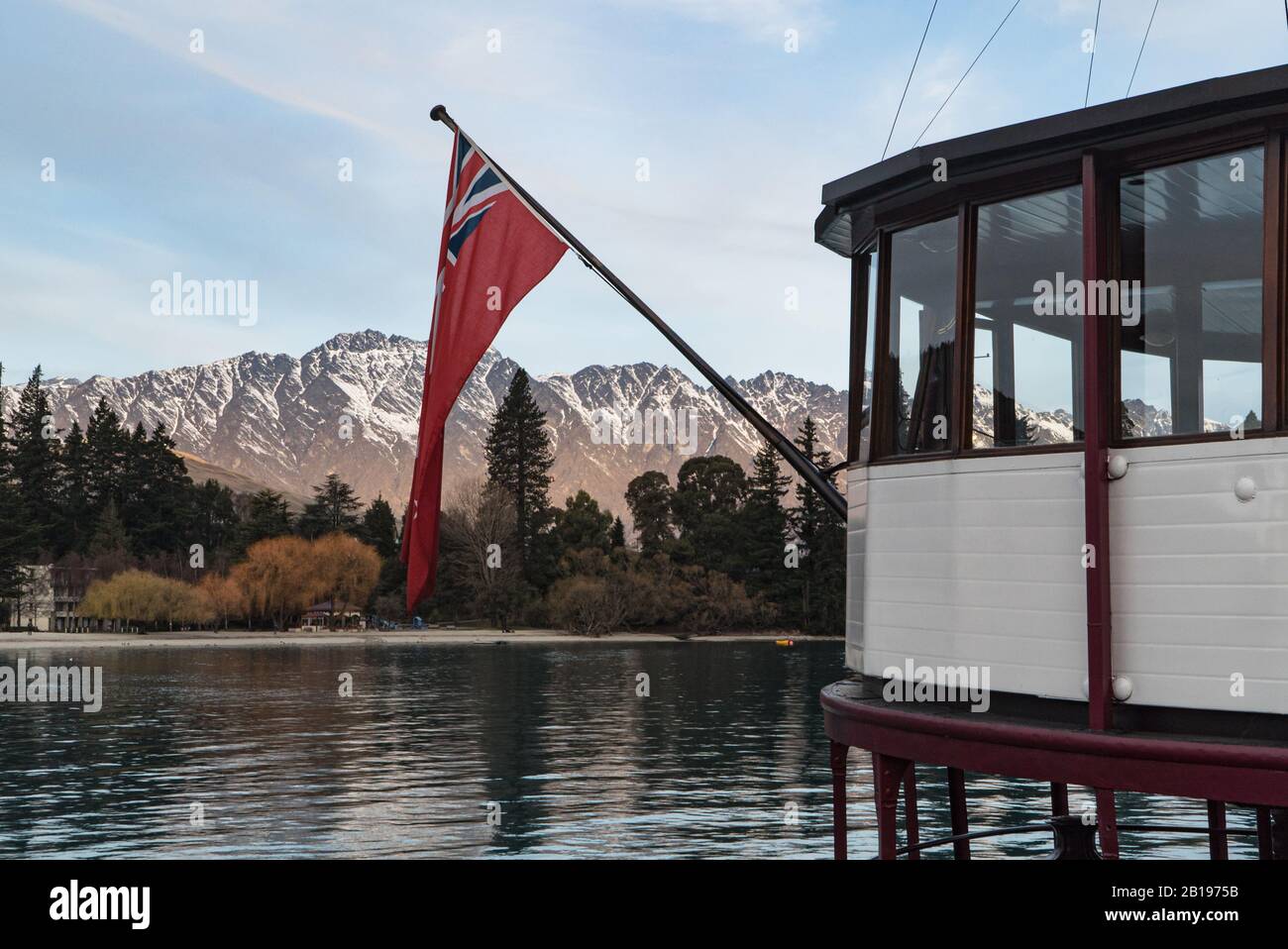 The ensign on the TSS Earnslaw with a mountain backdrop moored at Queenstown, New Zealand Stock Photo