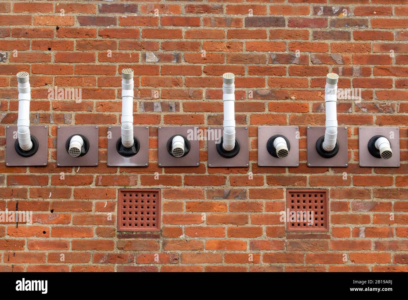 Alternating air intake and exhaust vents or pipes for boiler or furnace on the outside wall of a building Stock Photo