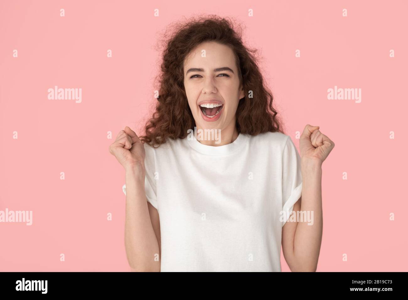 Overjoyed young lady clenching fists, celebrating success. Stock Photo