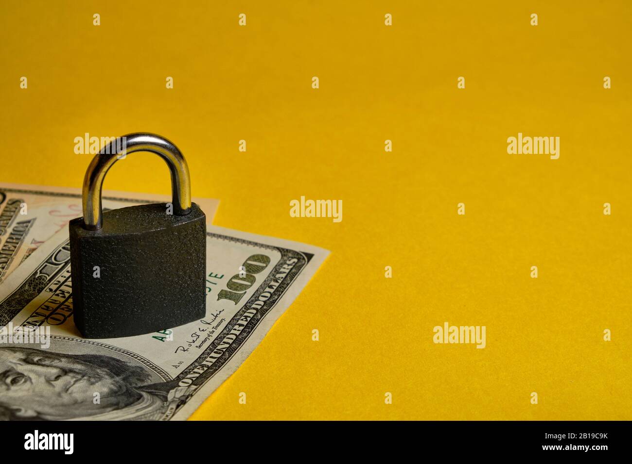 dollar banknotes and metal padlock at yellow background. Safety shopping, personal finances security, money savings concept. Stock Photo