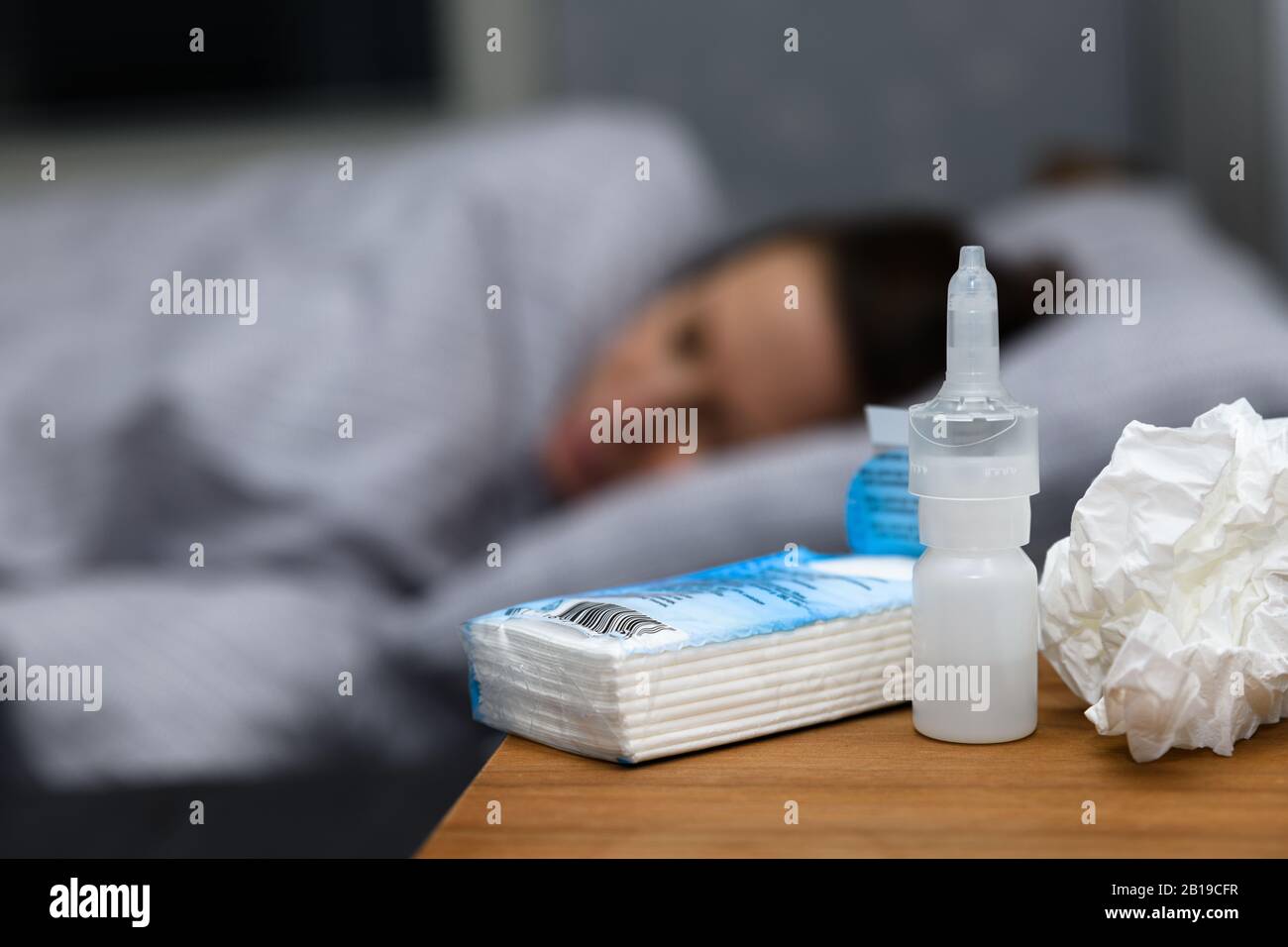Woman with a cold lying in bed at home trying to cure herself. Concept of catching this years flu and are now trying to cure,rest, use nasal spray Stock Photo