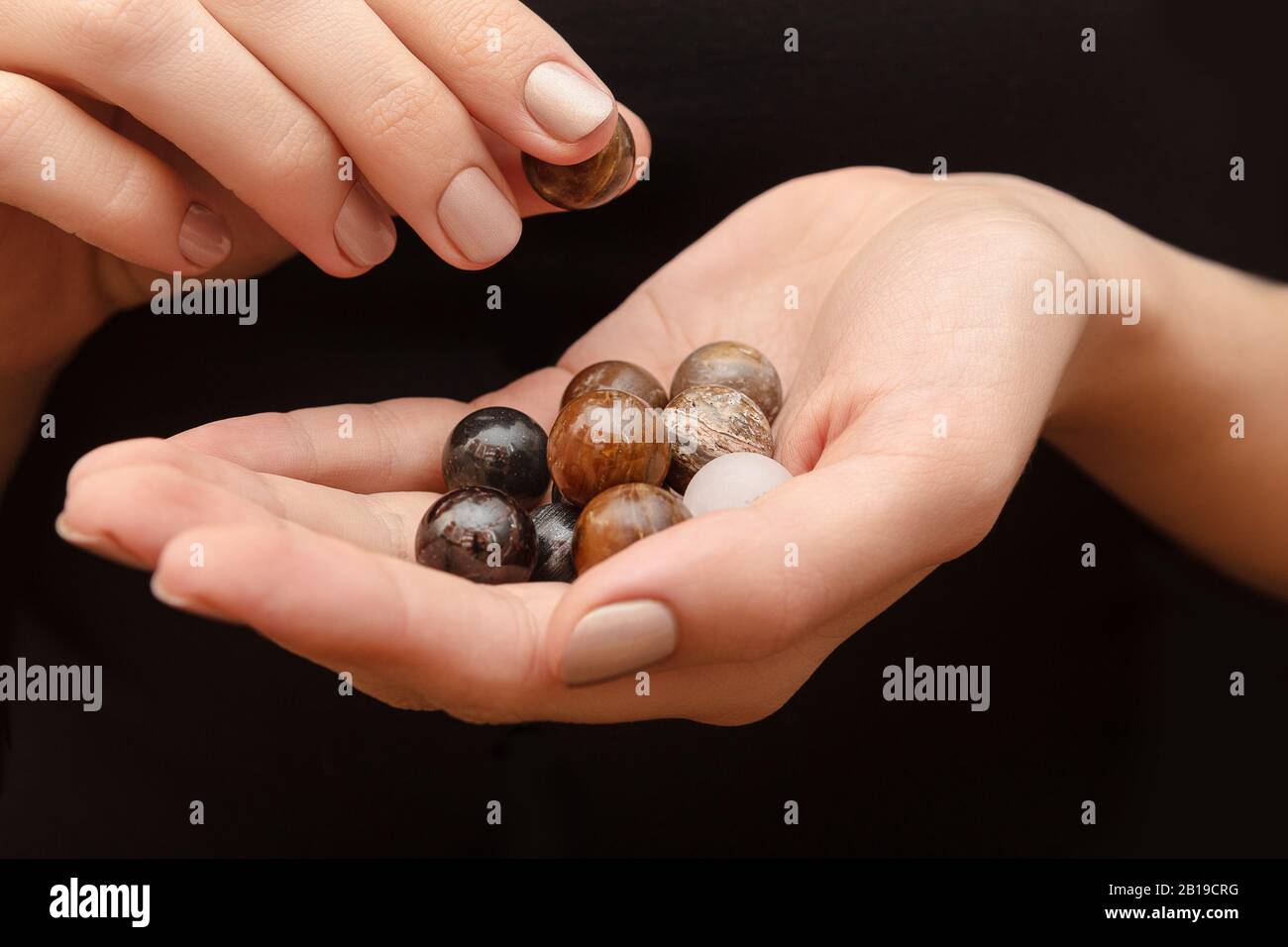 Round stones in female hands on black background. Stock Photo