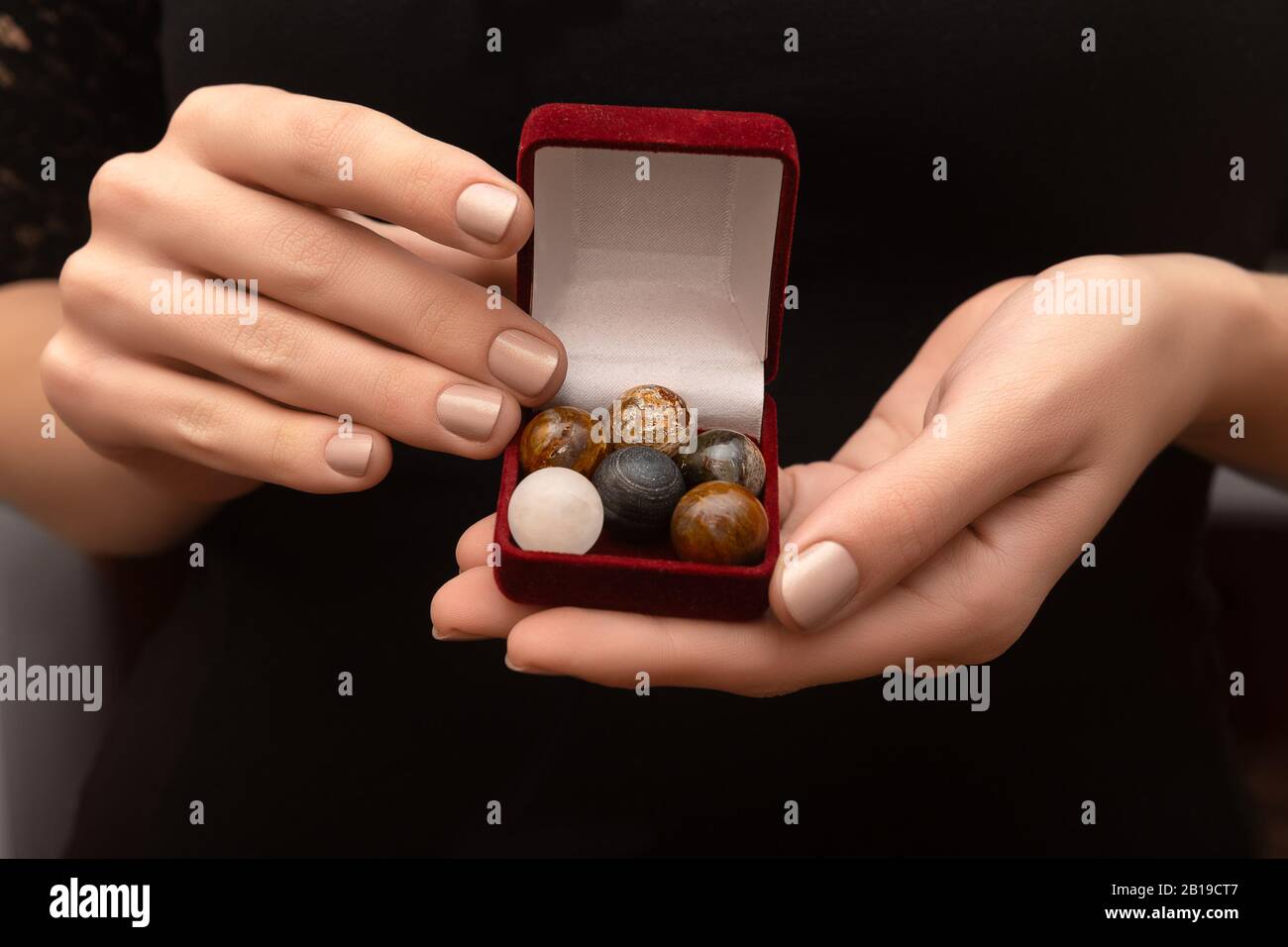 Sets of round stones in female hands on black background. Stock Photo